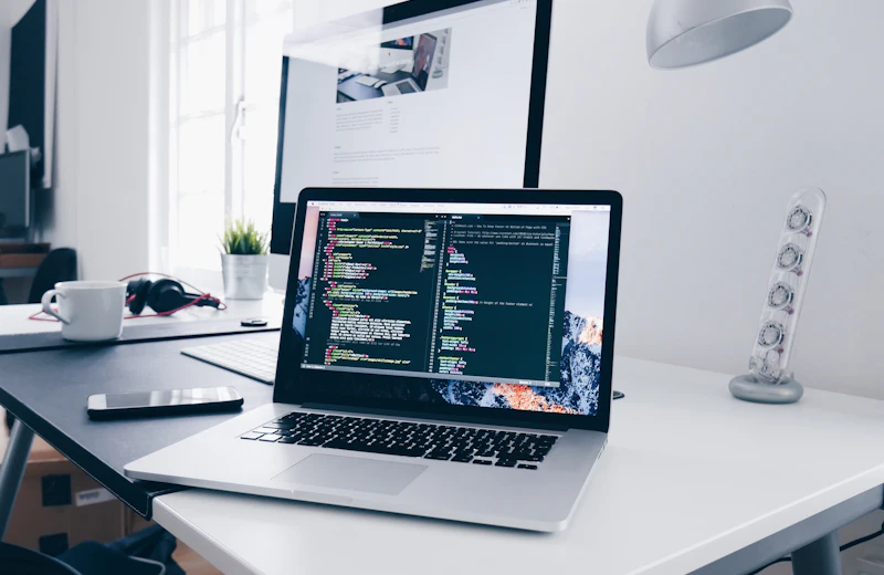 A laptop displaying source code on a desk